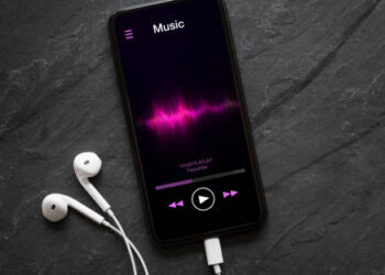 Music player on mobile phone with earphones on black background