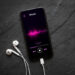 Music player on mobile phone with earphones on black background